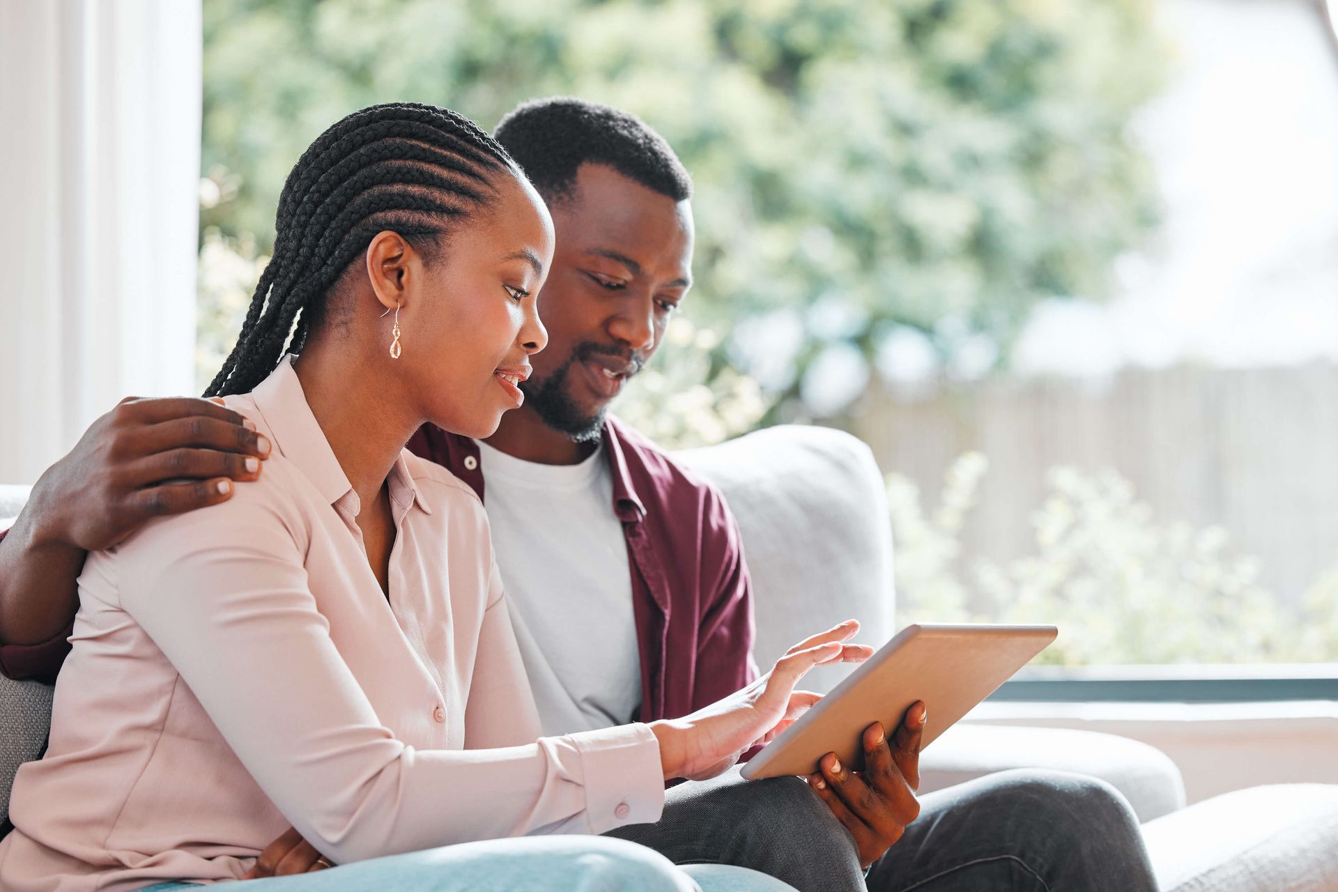 Couple sitting together on a couch reviewing information on a tablet