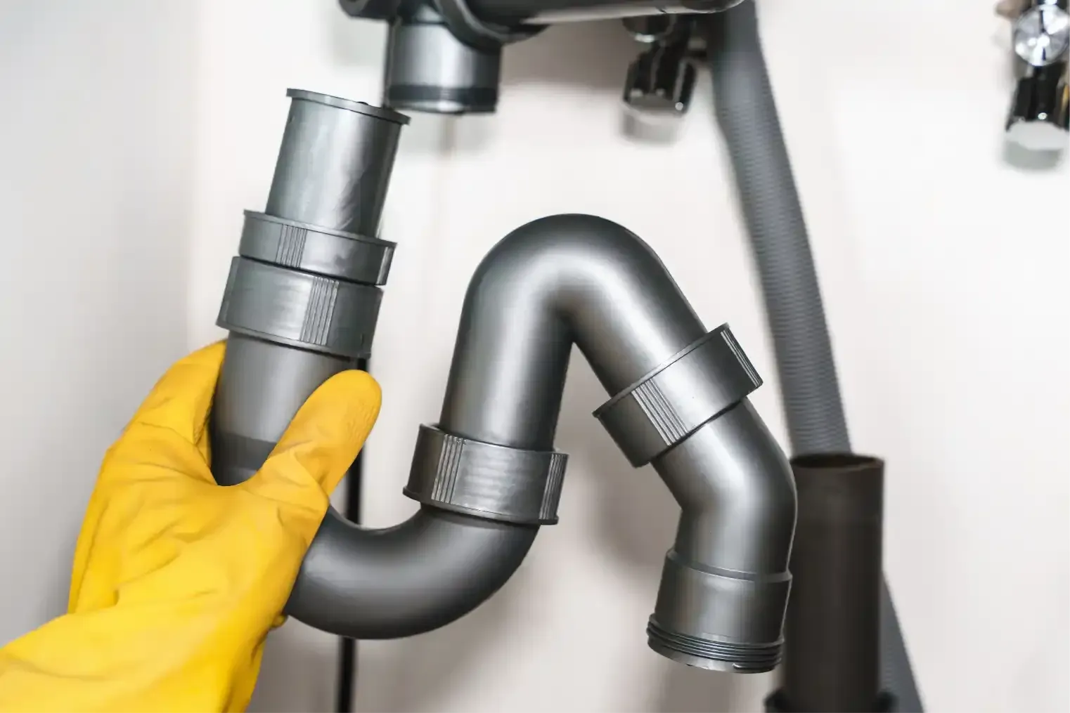 Hand tightening a pipe fitting under a sink with adjustable wrenches