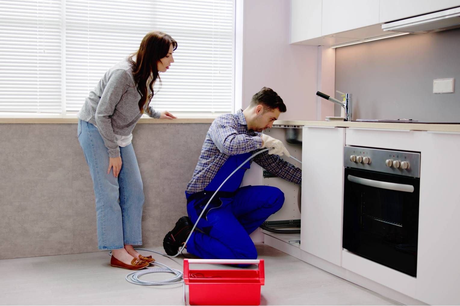 Hand tightening a pipe fitting under a sink with adjustable wrenches