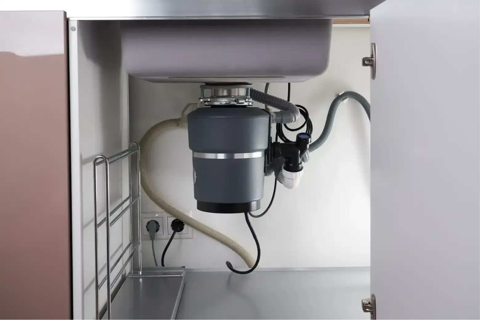 Hand tightening a pipe fitting under a sink with adjustable wrenches