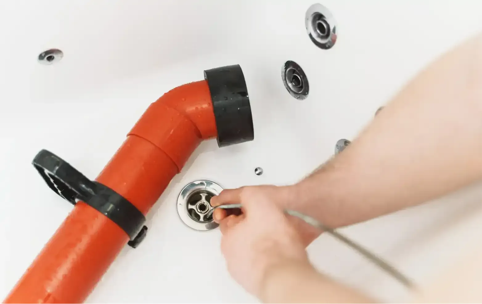 Hand tightening a pipe fitting under a sink with adjustable wrenches