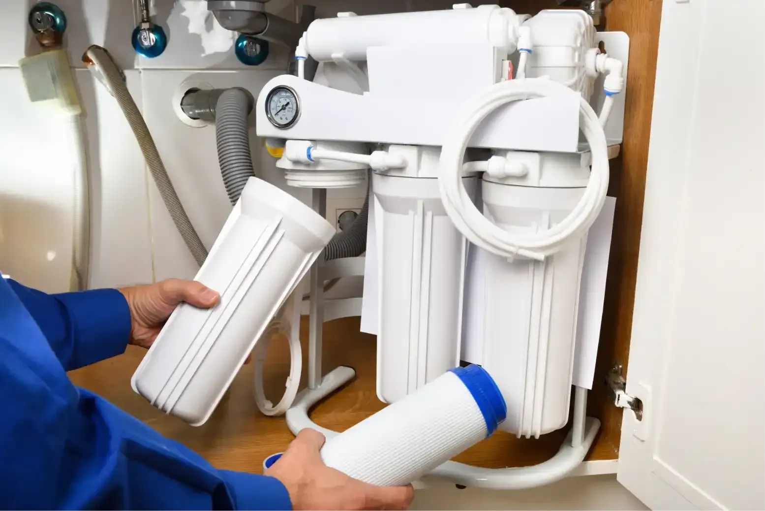 Hand tightening a pipe fitting under a sink with adjustable wrenches