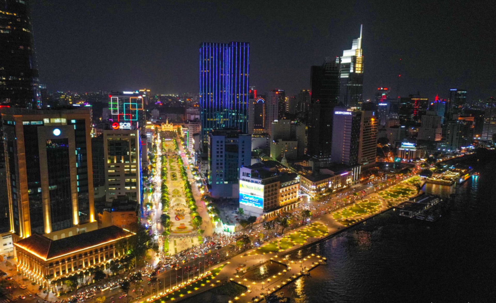 An aerial view of a city at night with a river in the foreground.