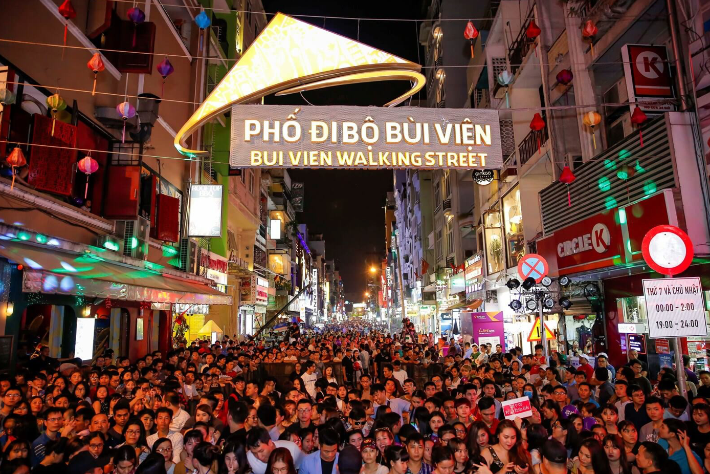 A crowd of people are walking down a busy street at night.