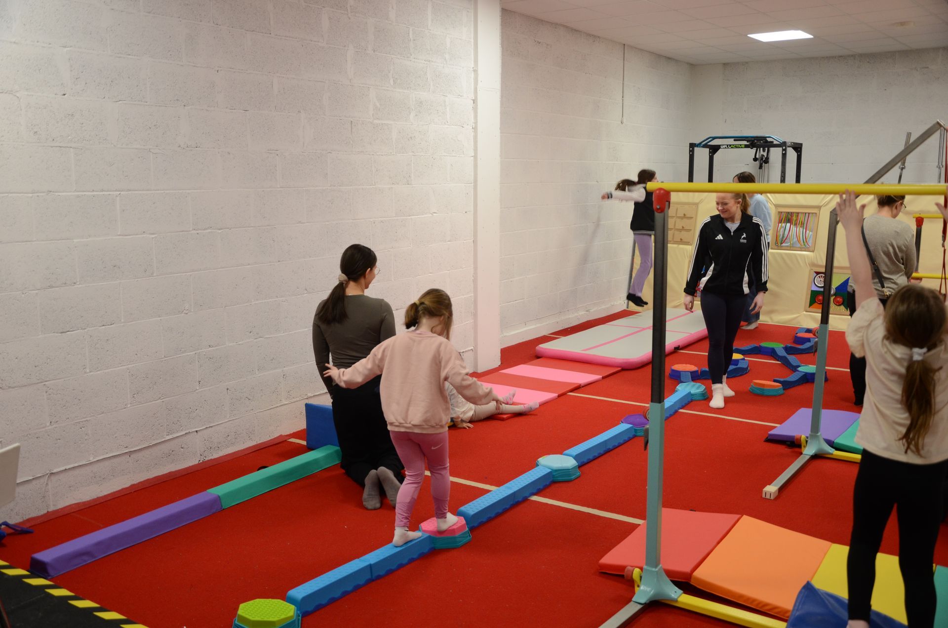 Two children performing a bridge pose on blue mats in a gym.