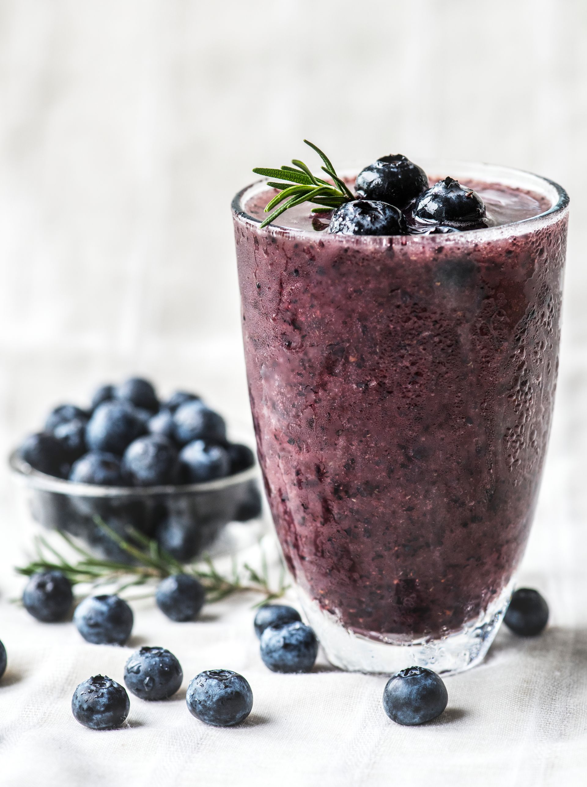 Een bosbessensmoothie in een glas met bosbessen erbovenop.