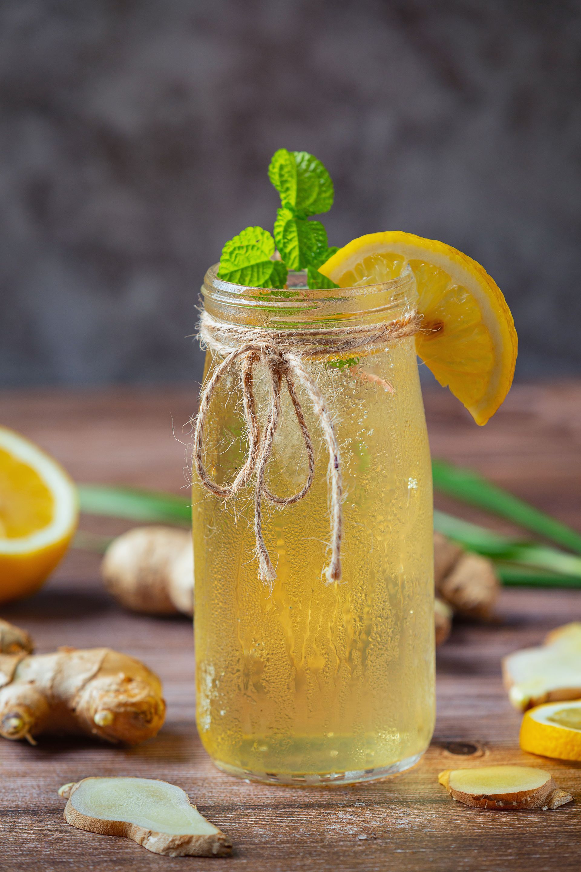 Een glas limonade met gember en munt op een houten tafel.