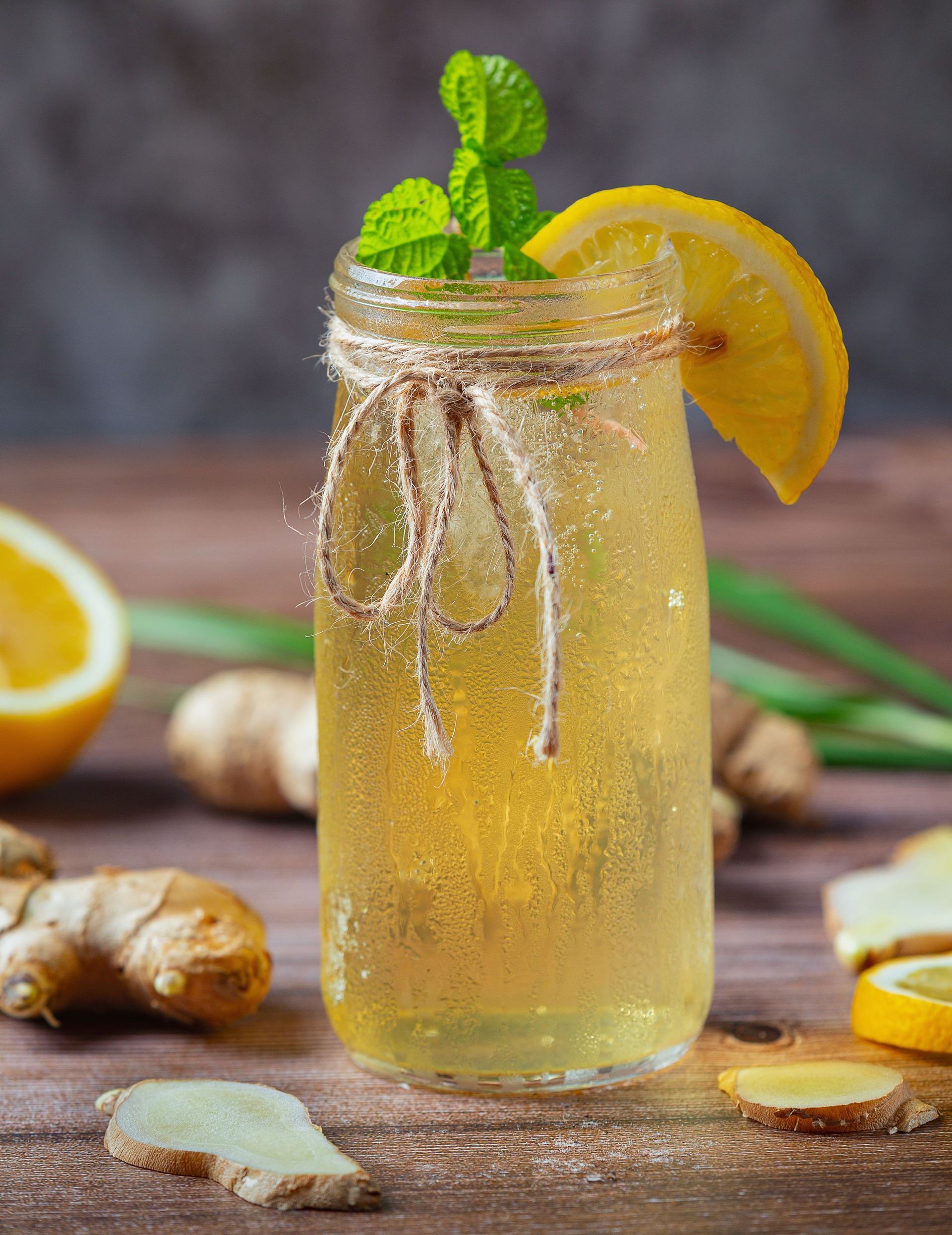 Een glas limonade met Yofelix gemberdrank en munt op een houten tafel.