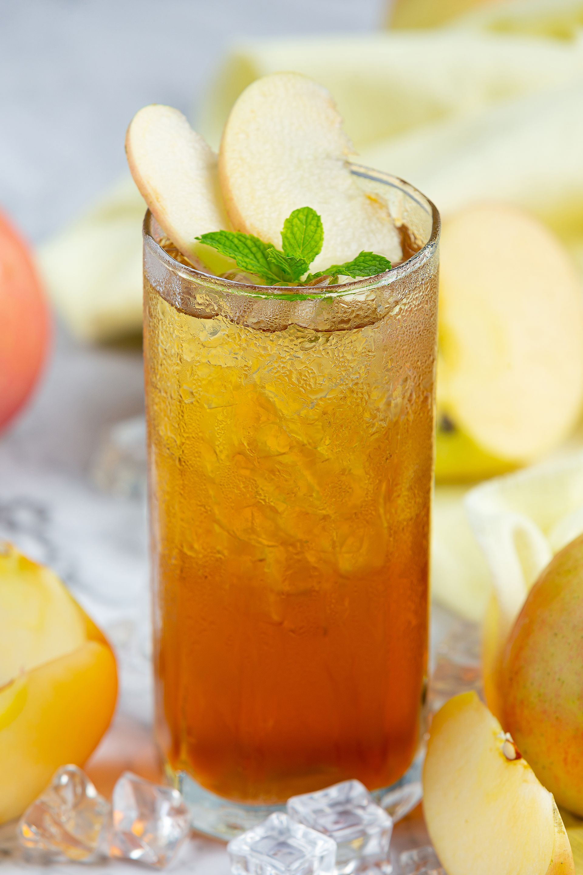 Een glas ijsthee met appelschijfjes en munt erbovenop.
