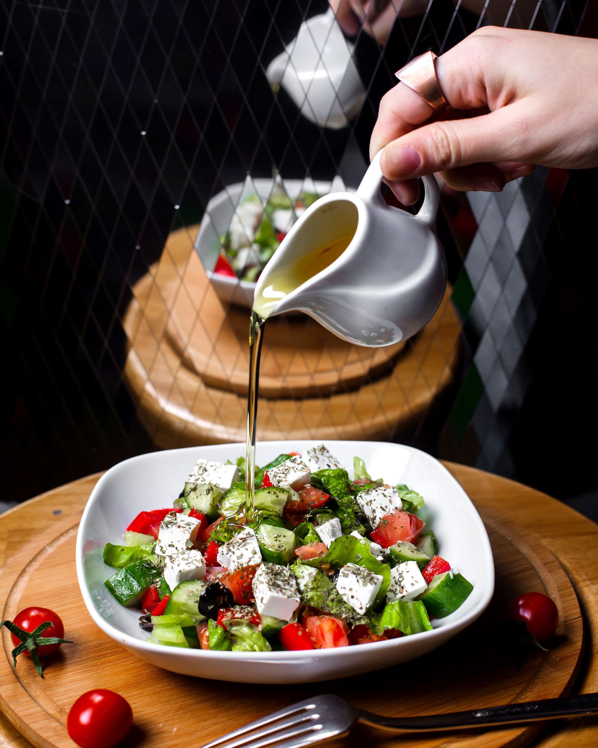 Een persoon giet olie over een salade in een kom.