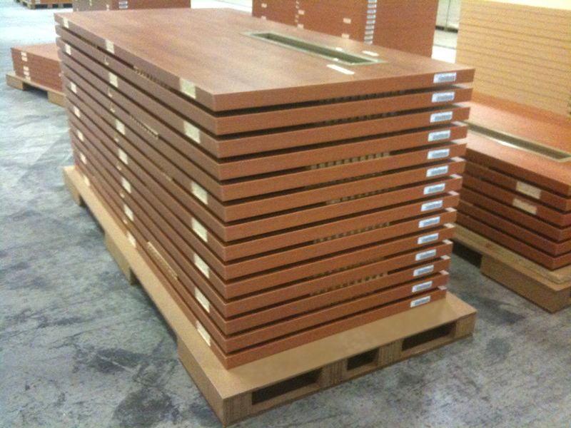 Stacked doors on a heavy-duty corrugated pallet with custom support blocks and bottom boards inside a manufacturing facility.