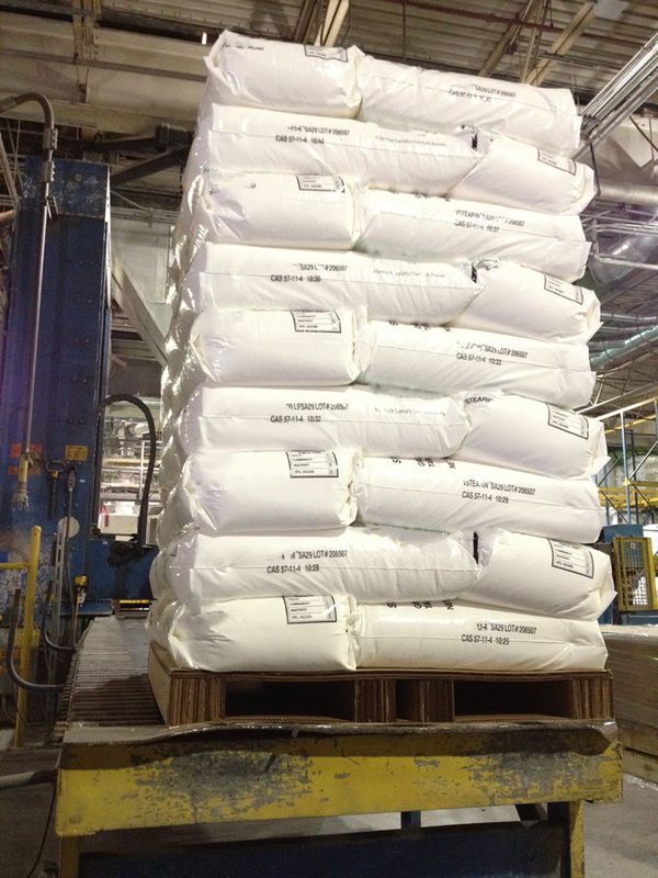 Heavy stack of white chemical bags on a corrugated pallet positioned on industrial loading equipment.