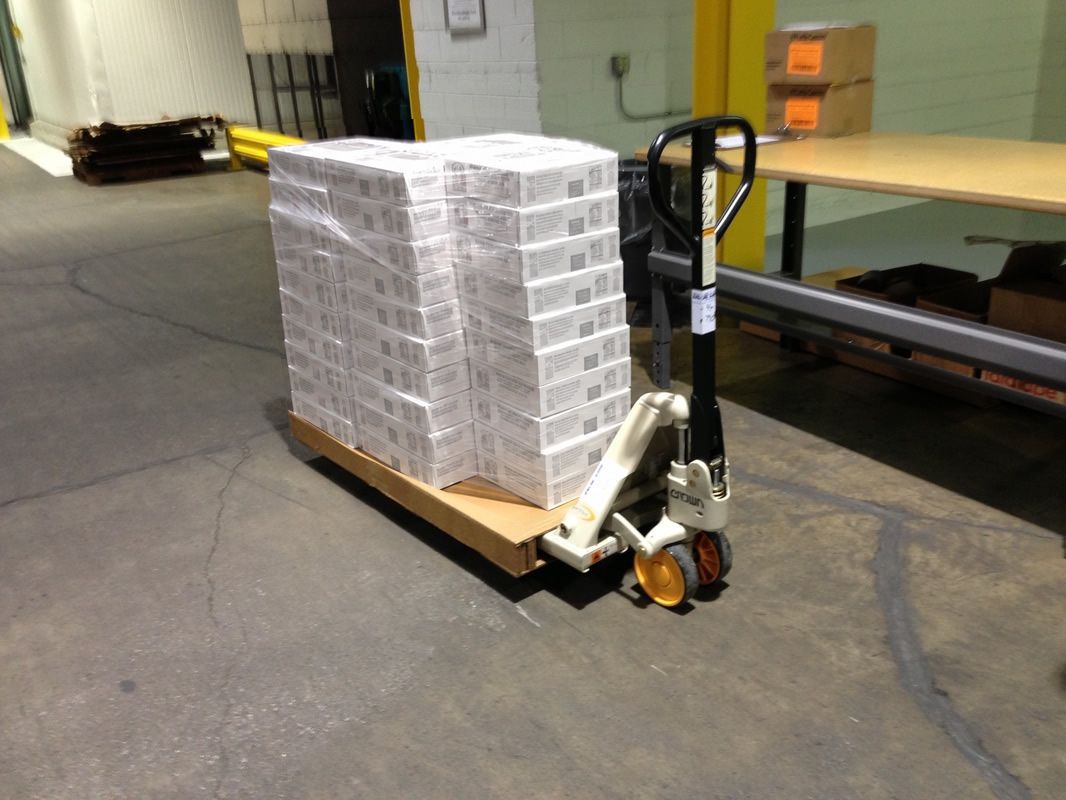 Stretch-wrapped cartons on a narrow corrugated pallet and pallet jack designed for delivery through standard doors.