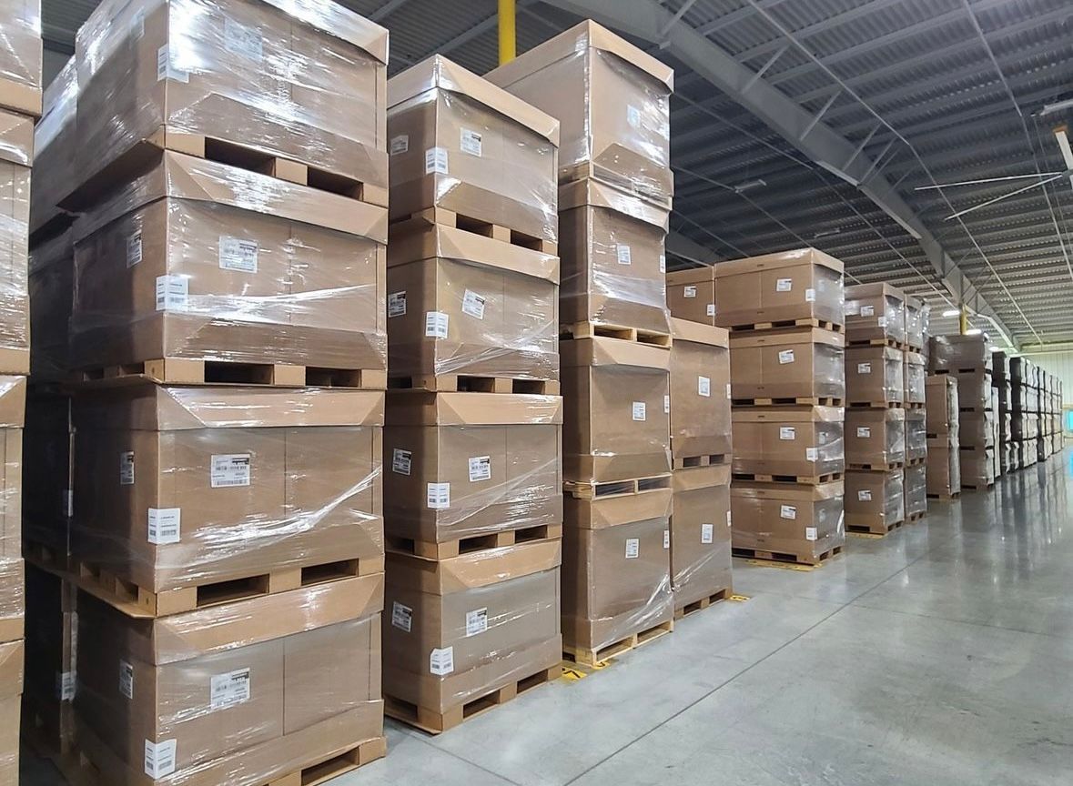 Rows of bulk containers stacked on corrugated tray pallets in a customer's warehouse, demonstrating the pallets in use.