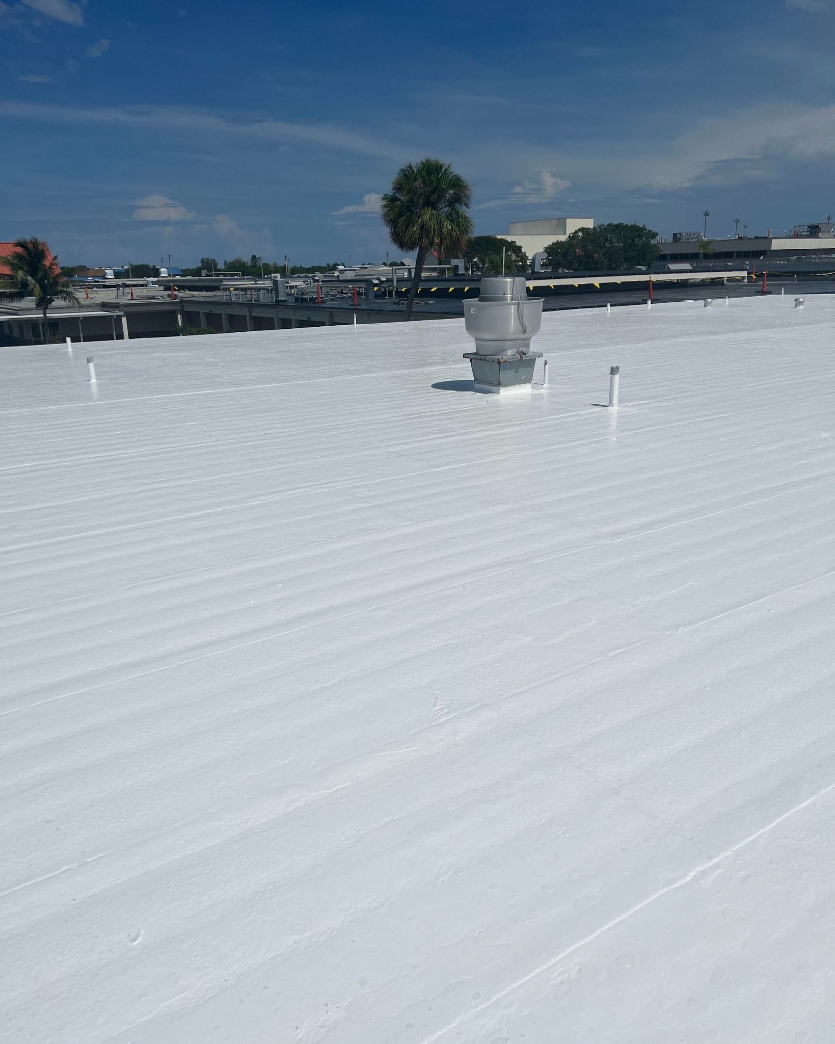Gloved hands use a nail gun to fasten roofing shingles on a roof