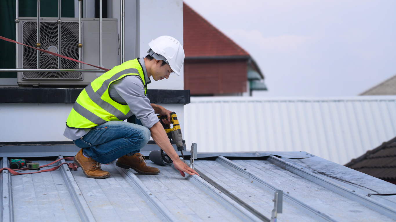Worker peeling damaged asphalt shingles from a roof after a storm