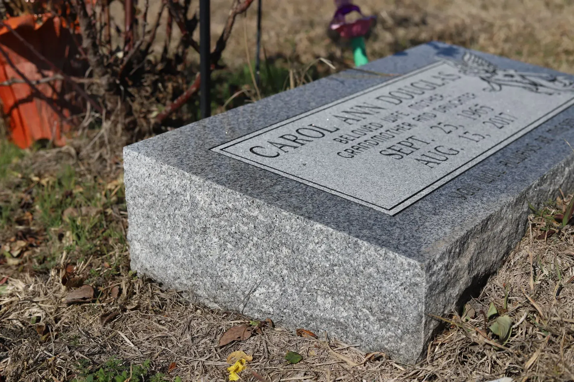 Gray granite headstone lying on ground; inscription reads