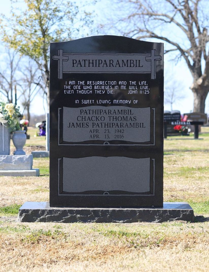 Black granite tombstone with inscriptions in a cemetery.