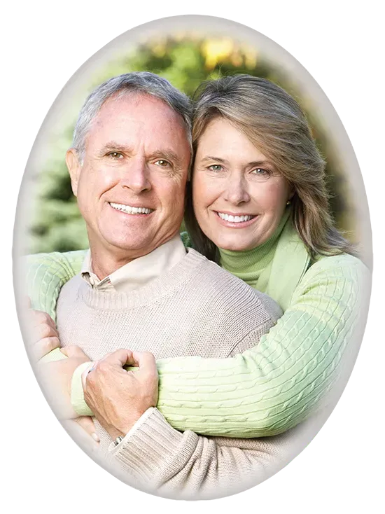 Smiling couple embracing outdoors. Woman in green sweater hugs man wearing a beige sweater.