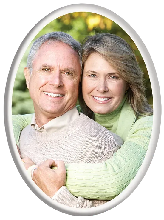 Smiling couple embracing outdoors. Woman in green sweater hugs man in beige sweater.