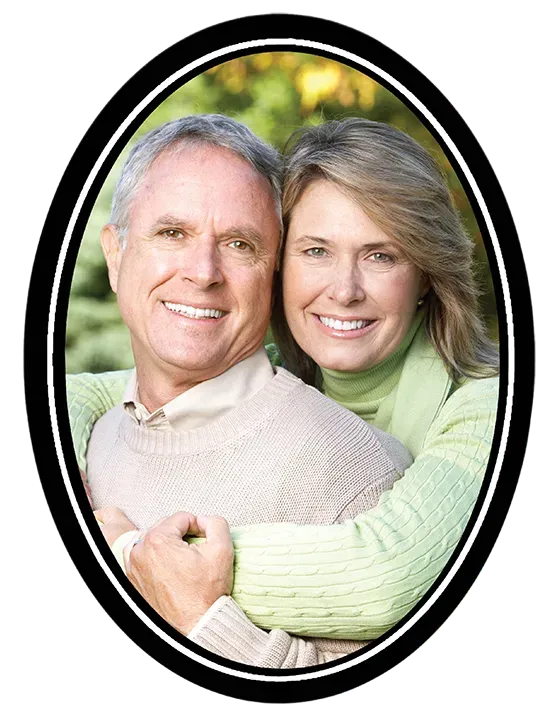 Couple embracing outdoors, smiling; oval frame with black and white border.