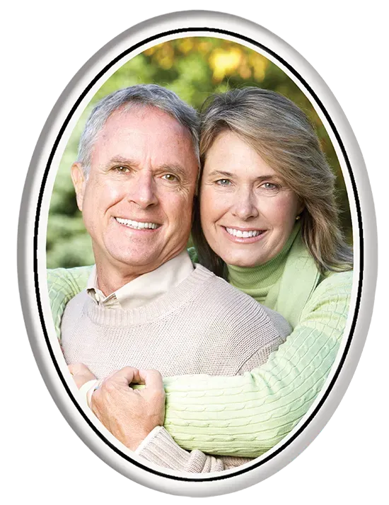 Smiling couple in an embrace, framed in an oval, with a blurred outdoor background.