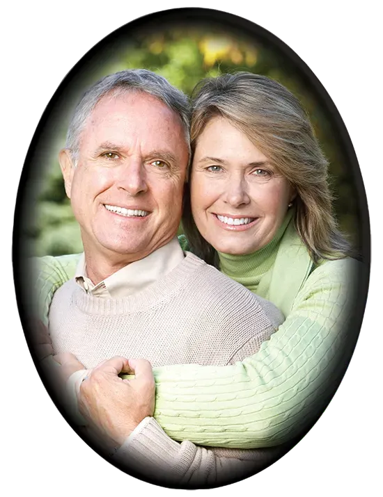 Smiling couple embracing, outside. Man in beige sweater, woman in green sweater. Oval frame.