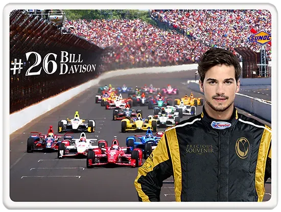 Race car driver Bill Davison stands near a race track with other cars racing in a crowd.