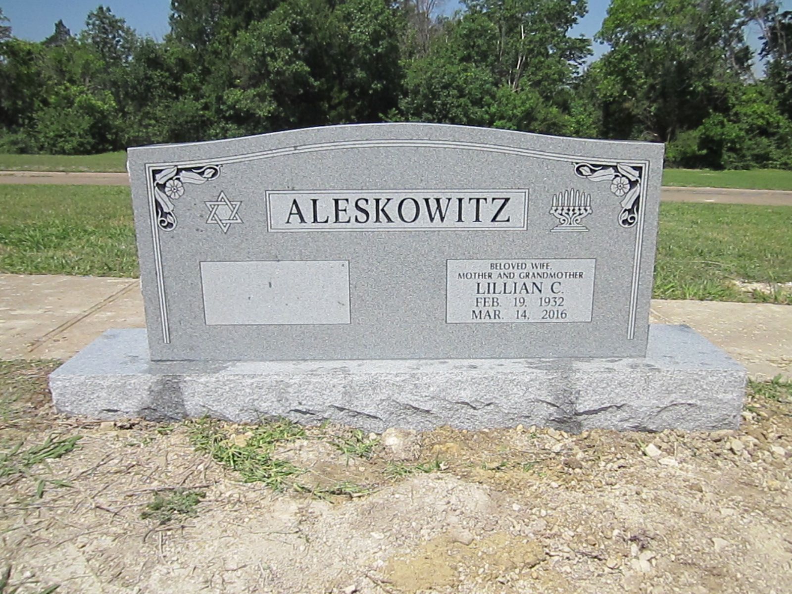 Gray Aleskowitz tombstone at a cemetery with inscription and floral designs.
