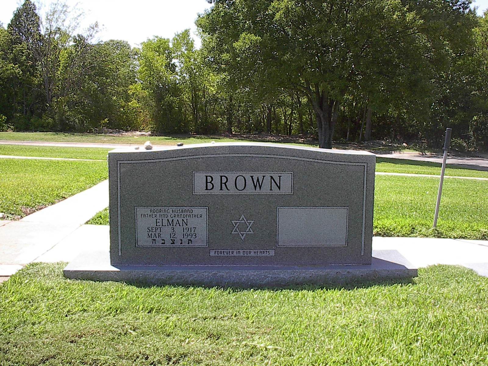 Gray headstone in a grassy cemetery, with