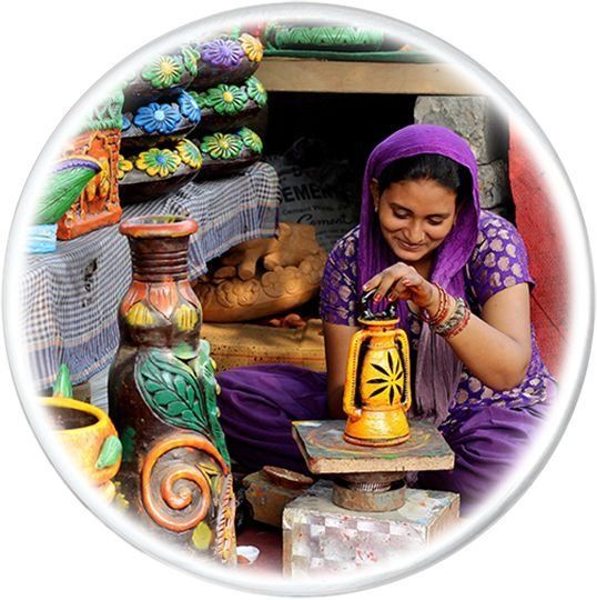 Woman in purple decorates a yellow lantern amidst pottery.