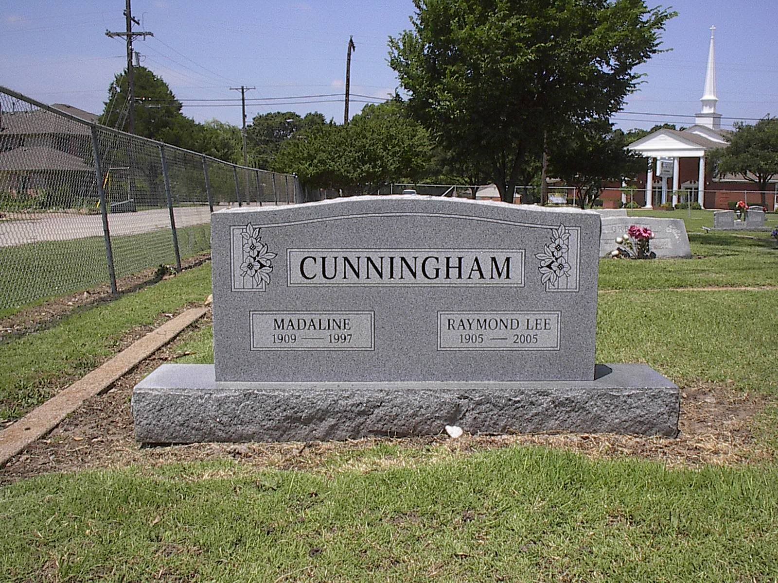 Gray granite headstone in a cemetery; reads
