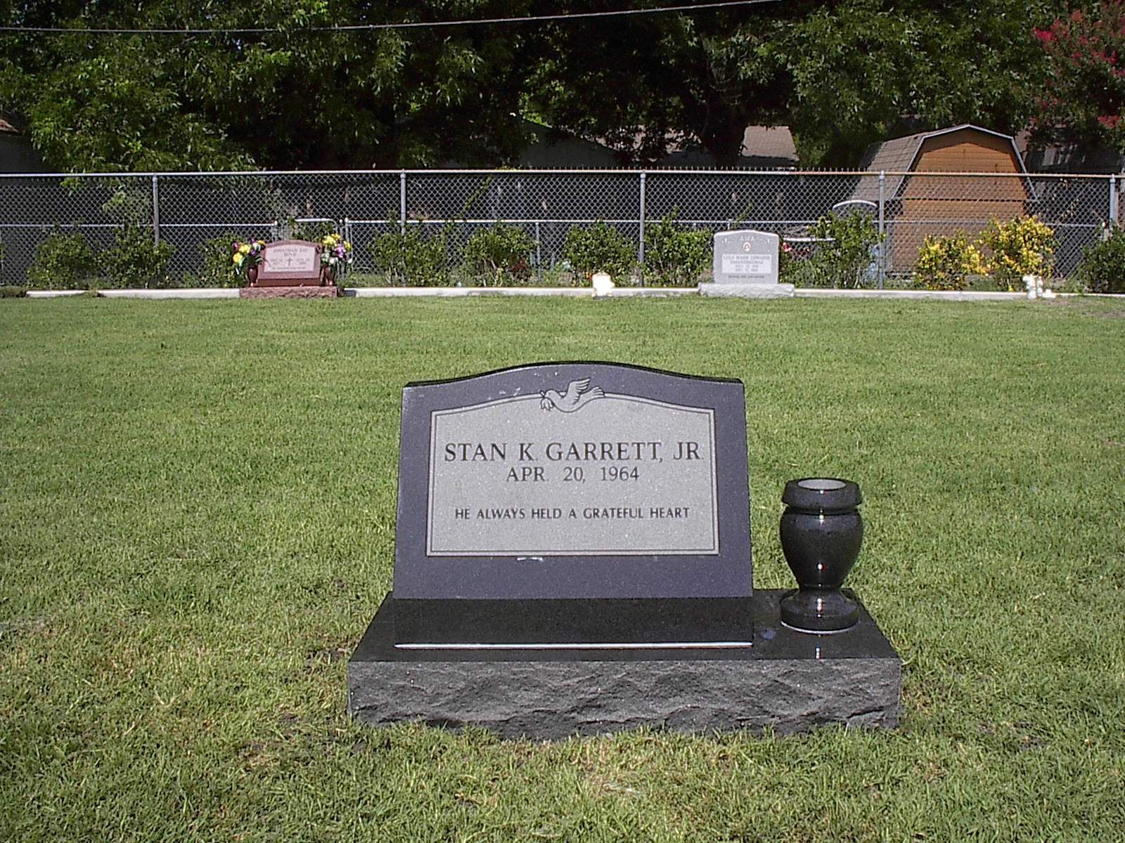Headstone for Stan E. Garrett Jr. in a grassy cemetery. The tombstone is black.