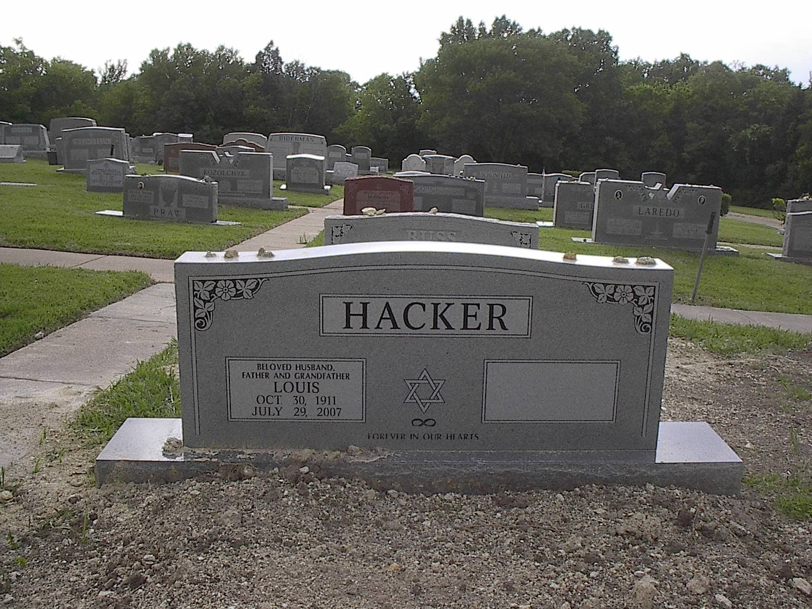 Gray Hacker family tombstone in a cemetery; other headstones and trees visible.