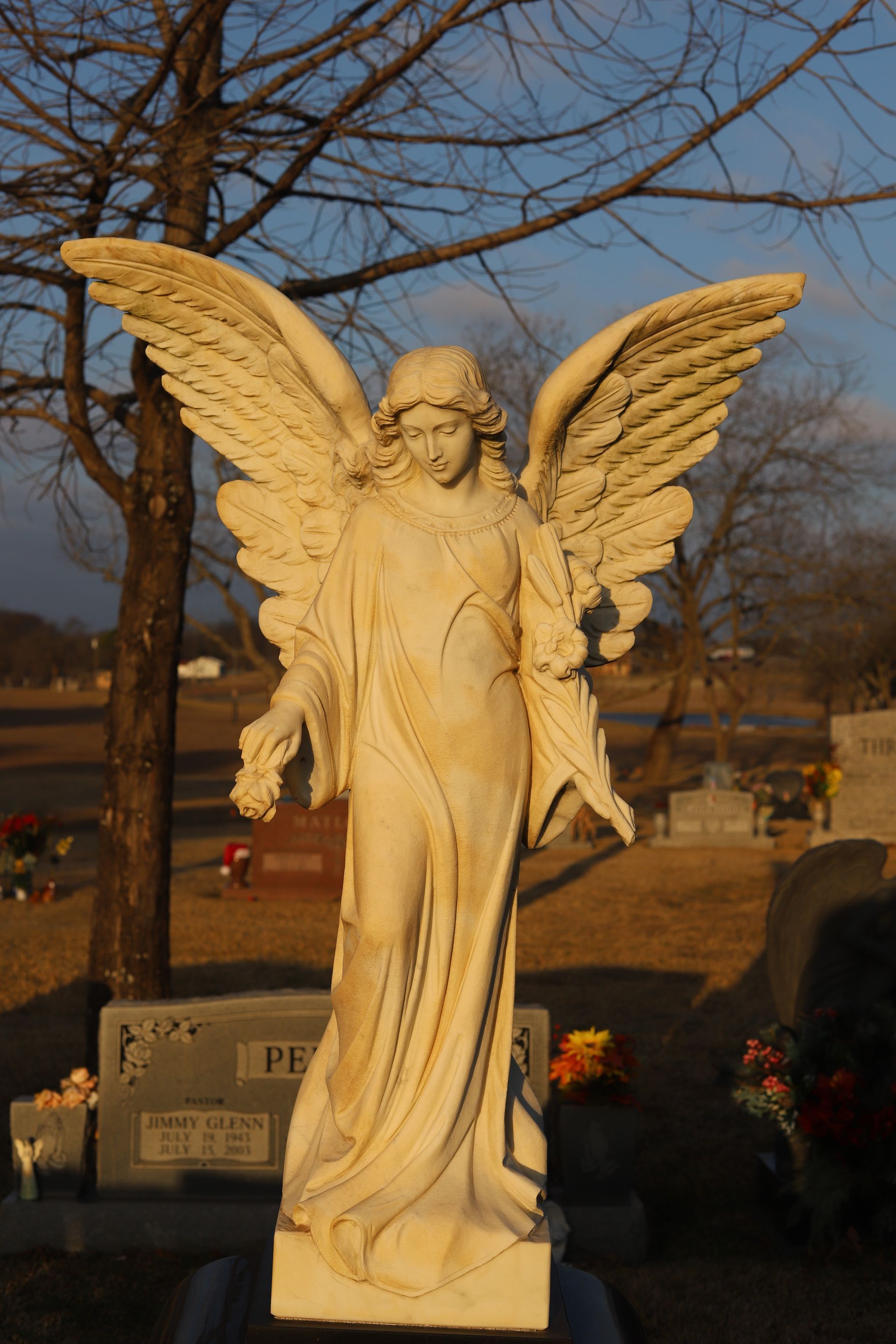 Statue of an angel with outstretched wings in a cemetery.