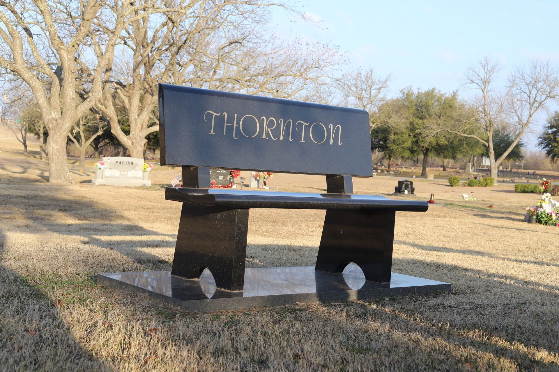 Black granite bench in a cemetery with the name 