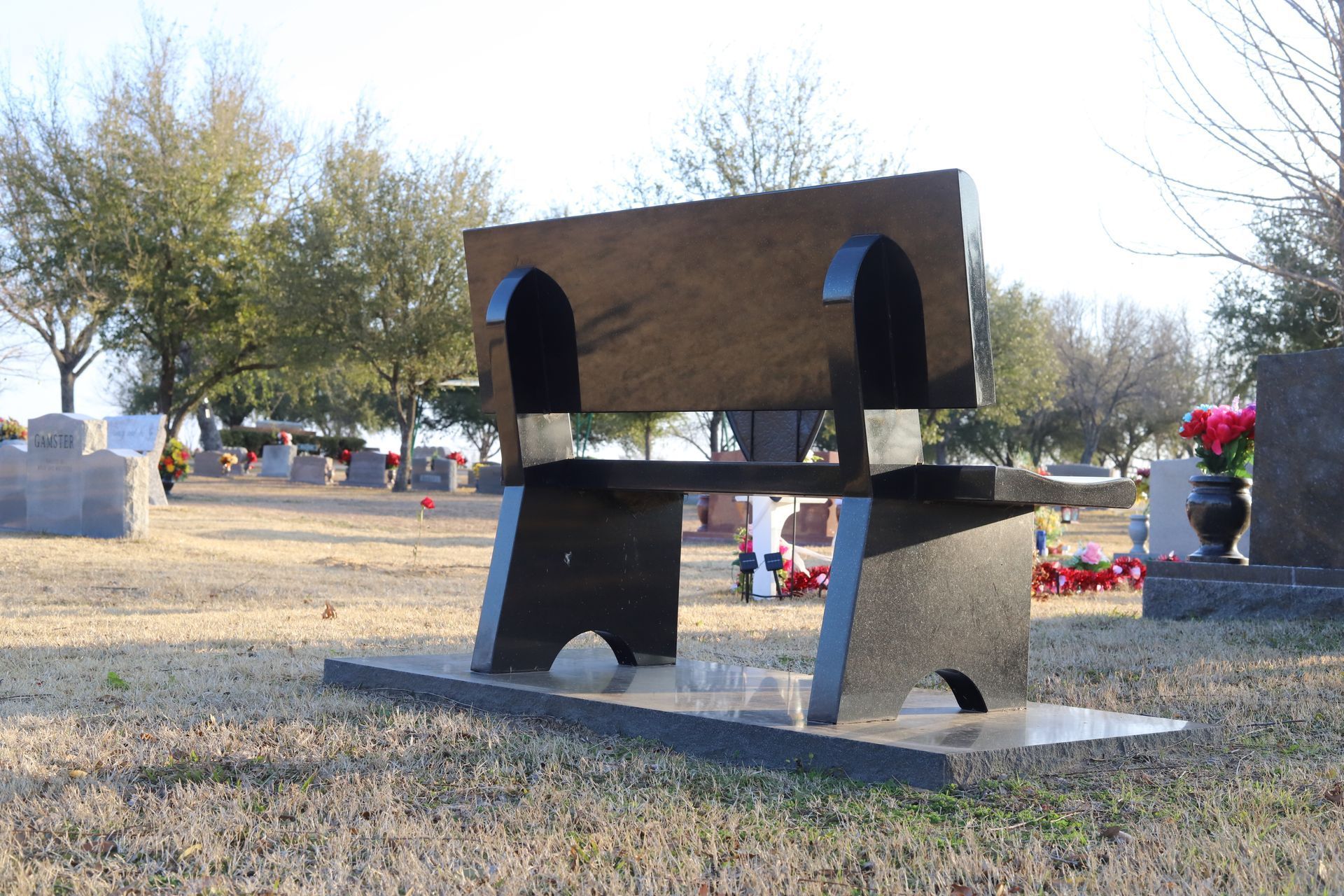 Black granite memorial bench in a cemetery.