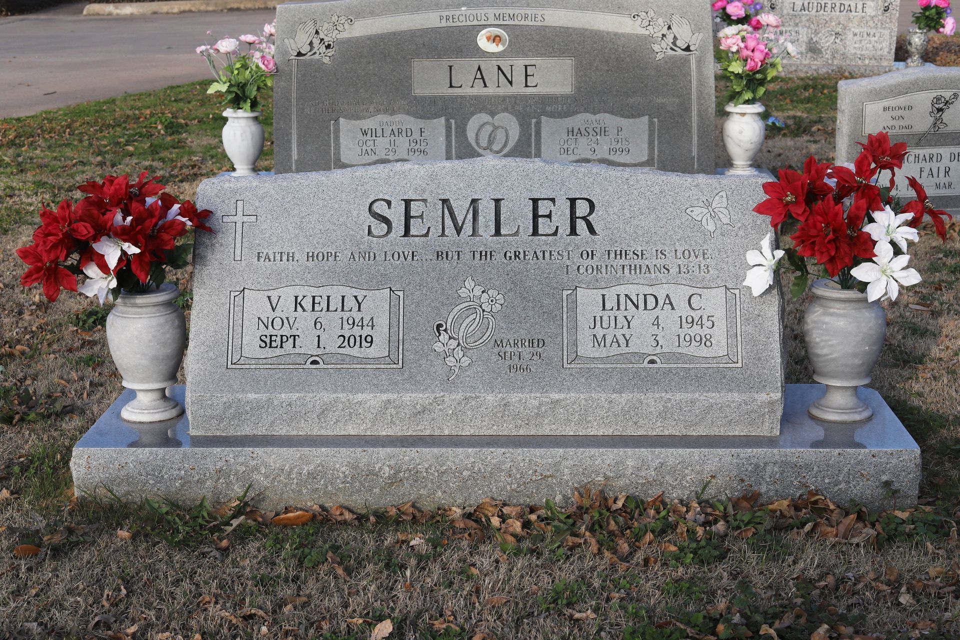 Gravestone for the Semler family with vases of flowers, set in a grassy cemetery.