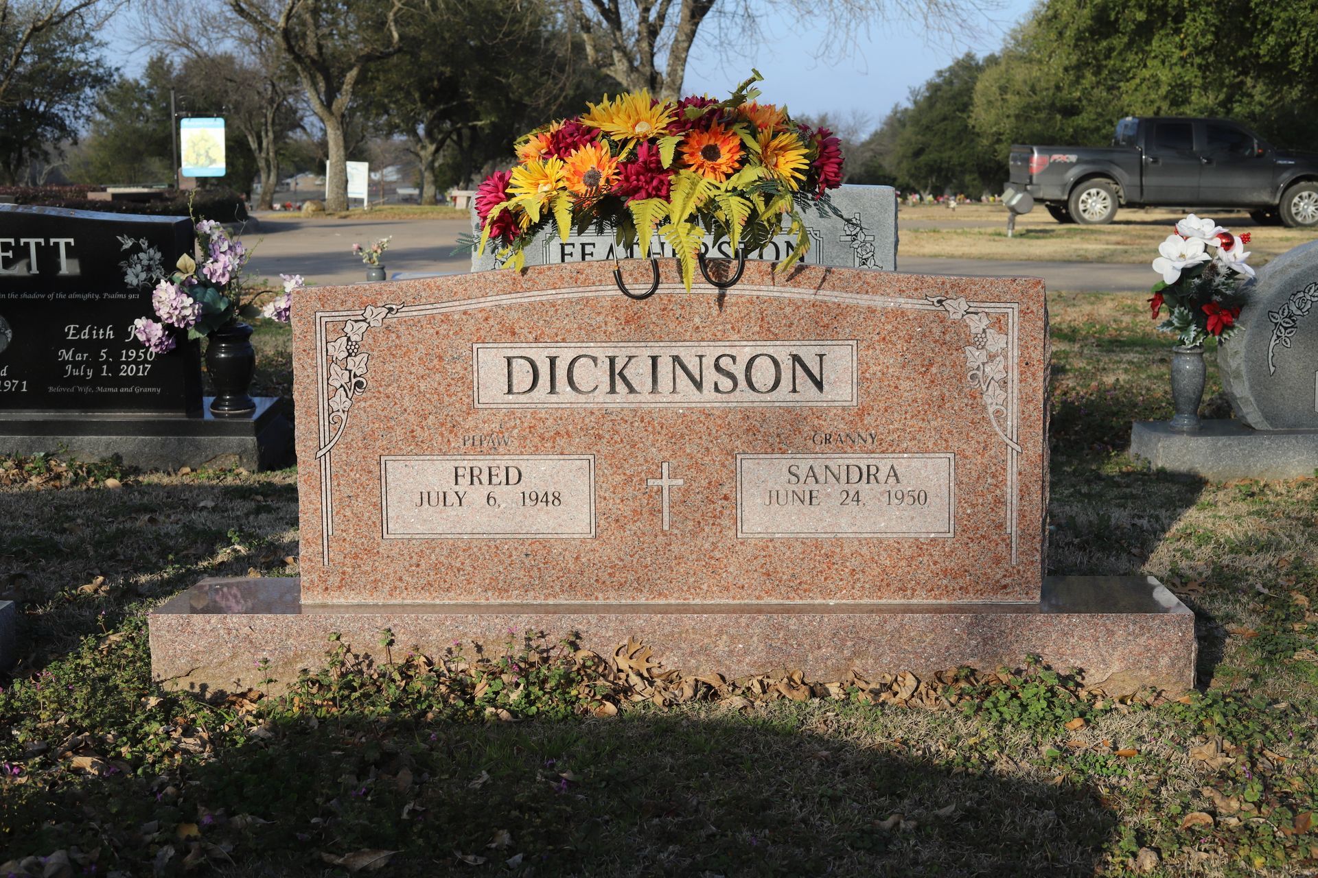 Tombstone of the Dickinson family in a cemetery; dates and flowers on top.