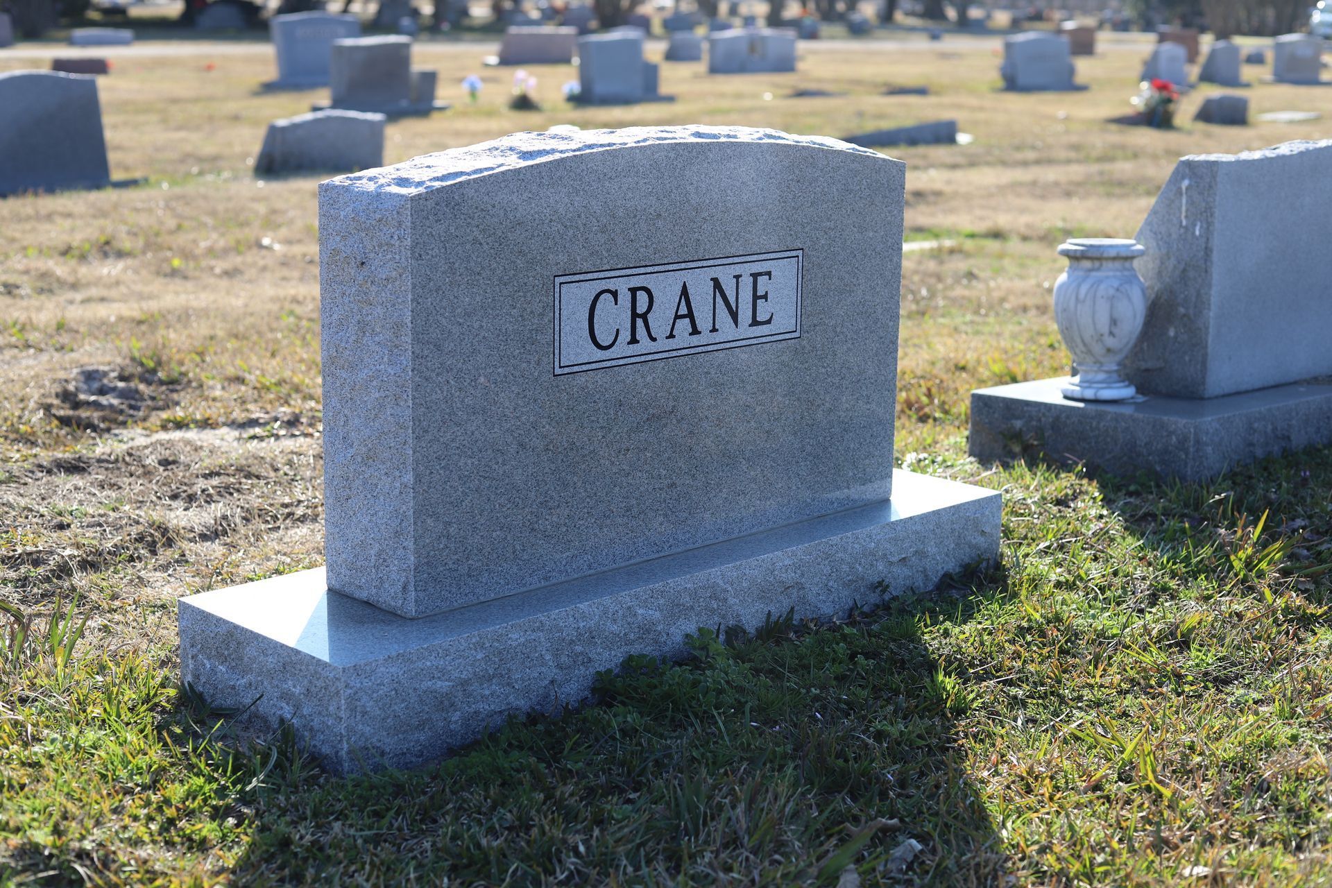 A gray headstone in a cemetery with the name