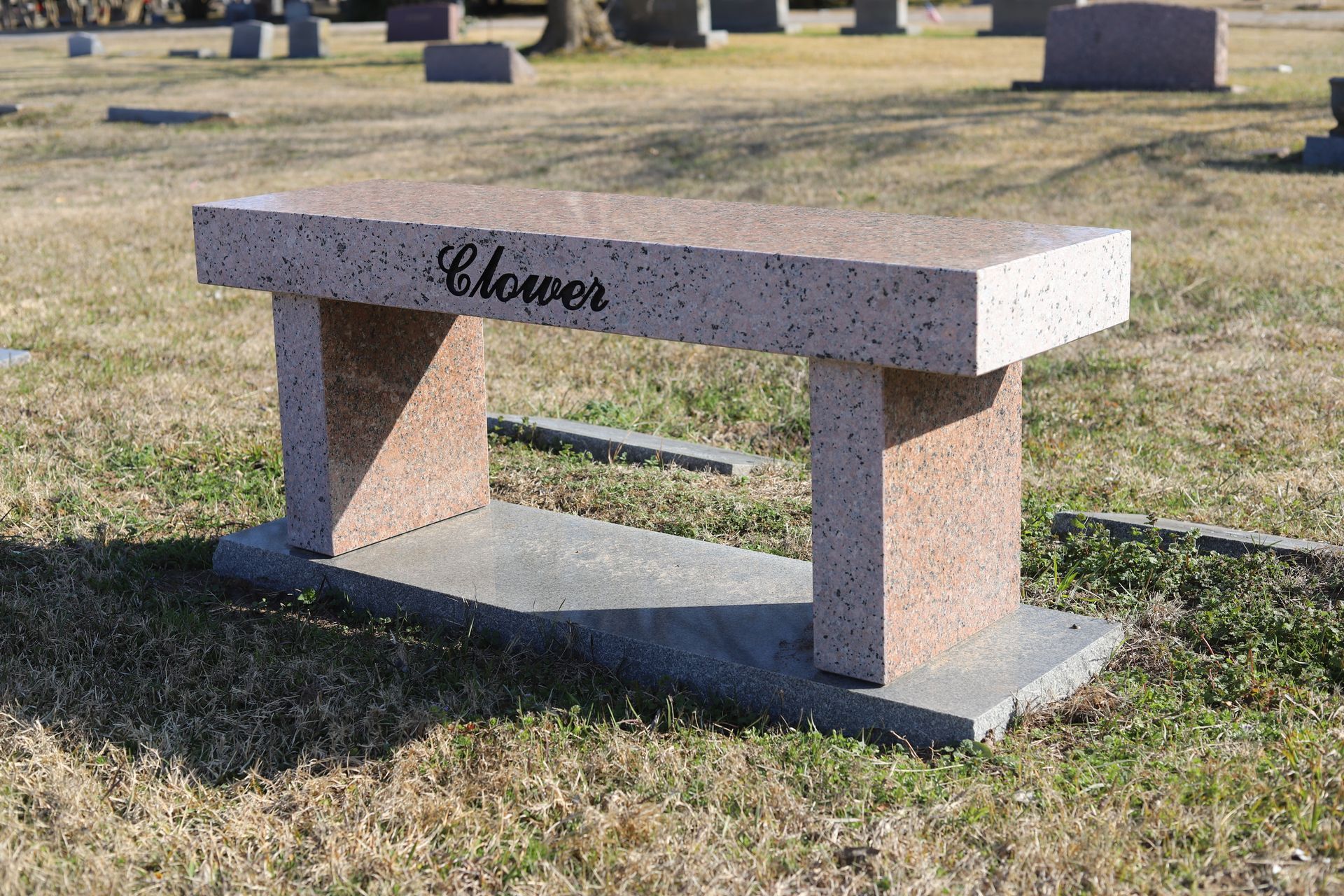 A granite bench in a cemetery with 