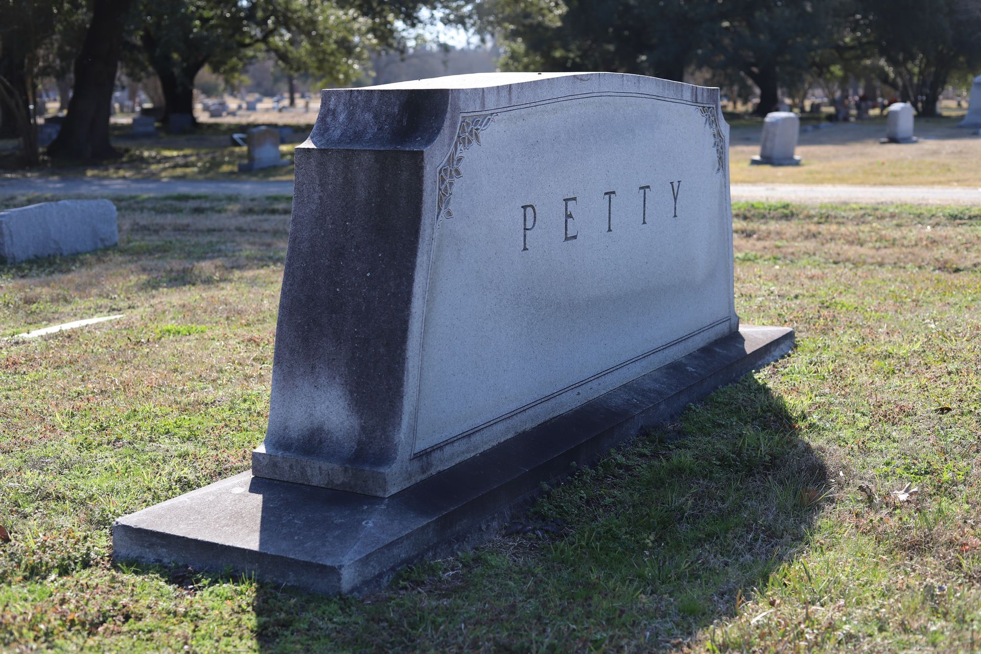 Gray stone tombstone in a grassy cemetery, reads 