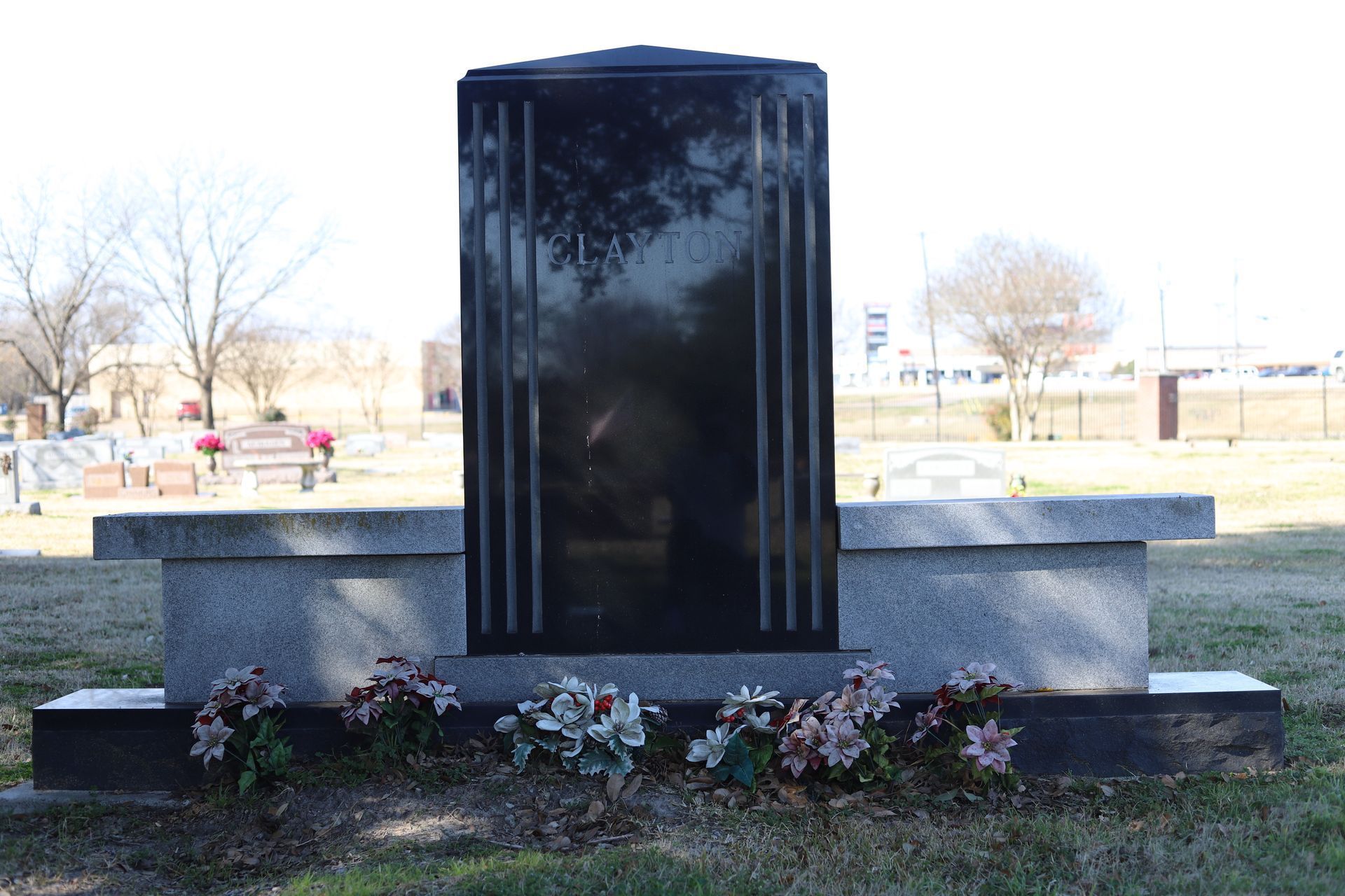 Black granite monument with floral decorations in a cemetery.
