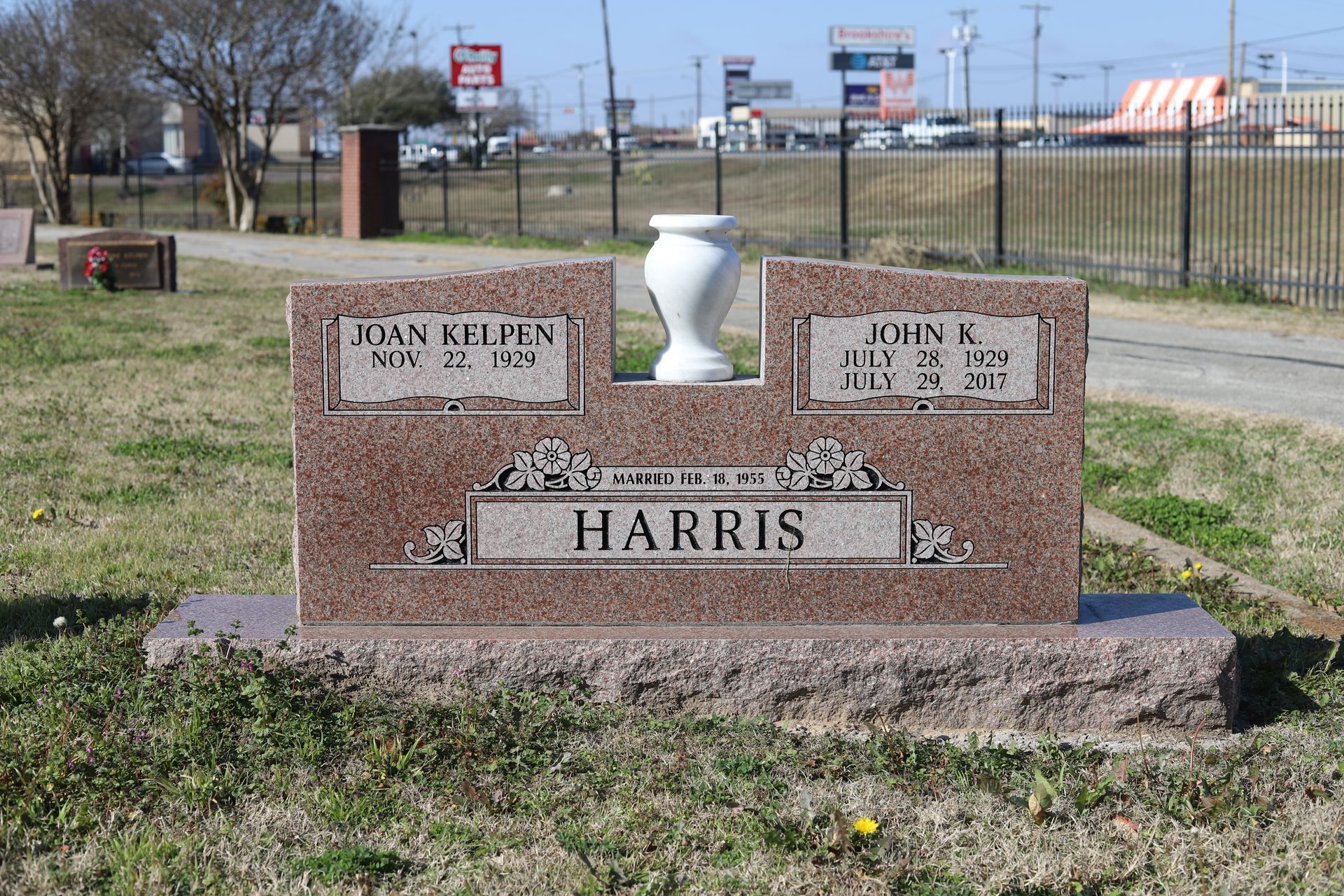 Red granite headstone in a cemetery; reads