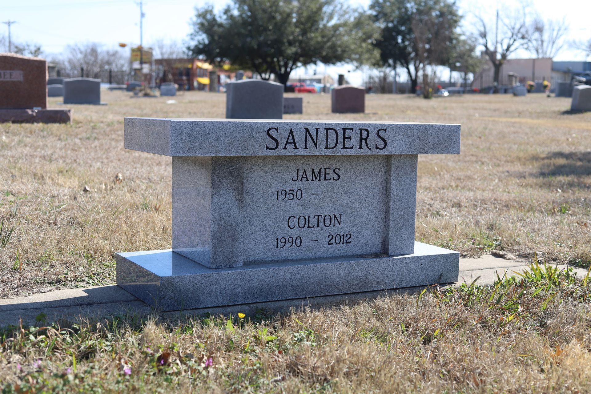 Gray granite headstone in a cemetery; name 