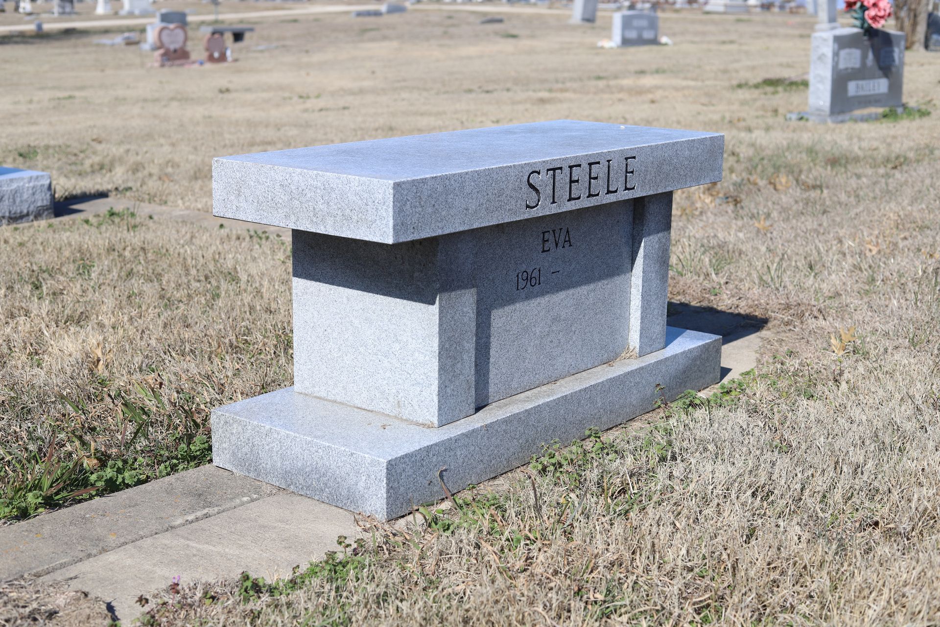 Gray granite bench gravestone in a cemetery; name 