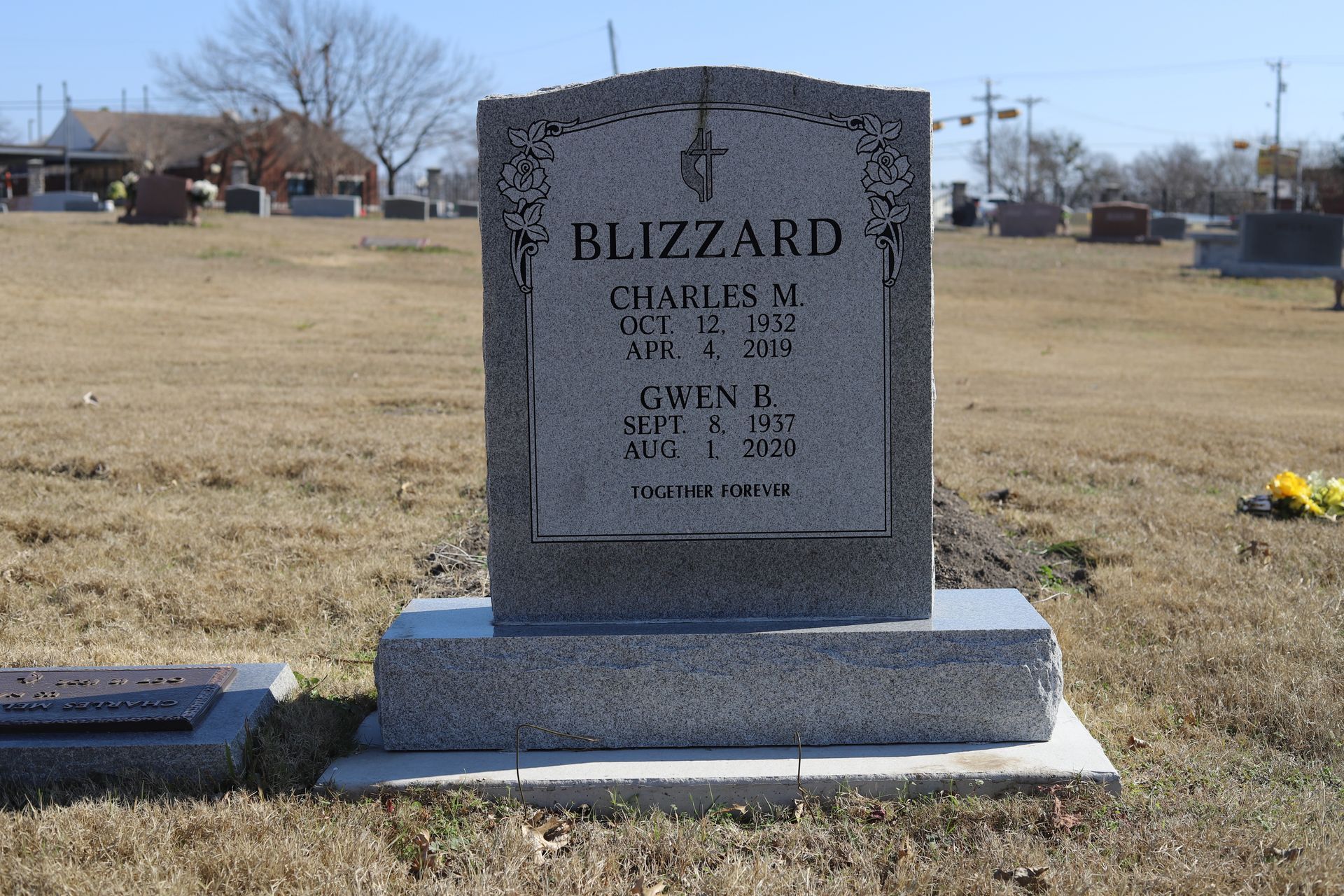Gray tombstone in a cemetery; reads