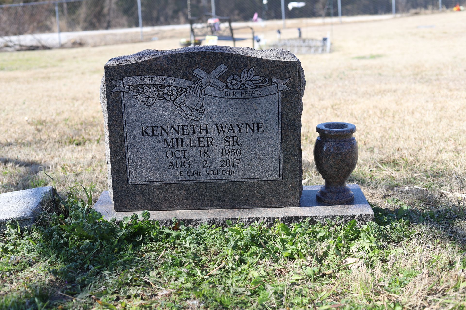 Gray headstone in a cemetery; reads