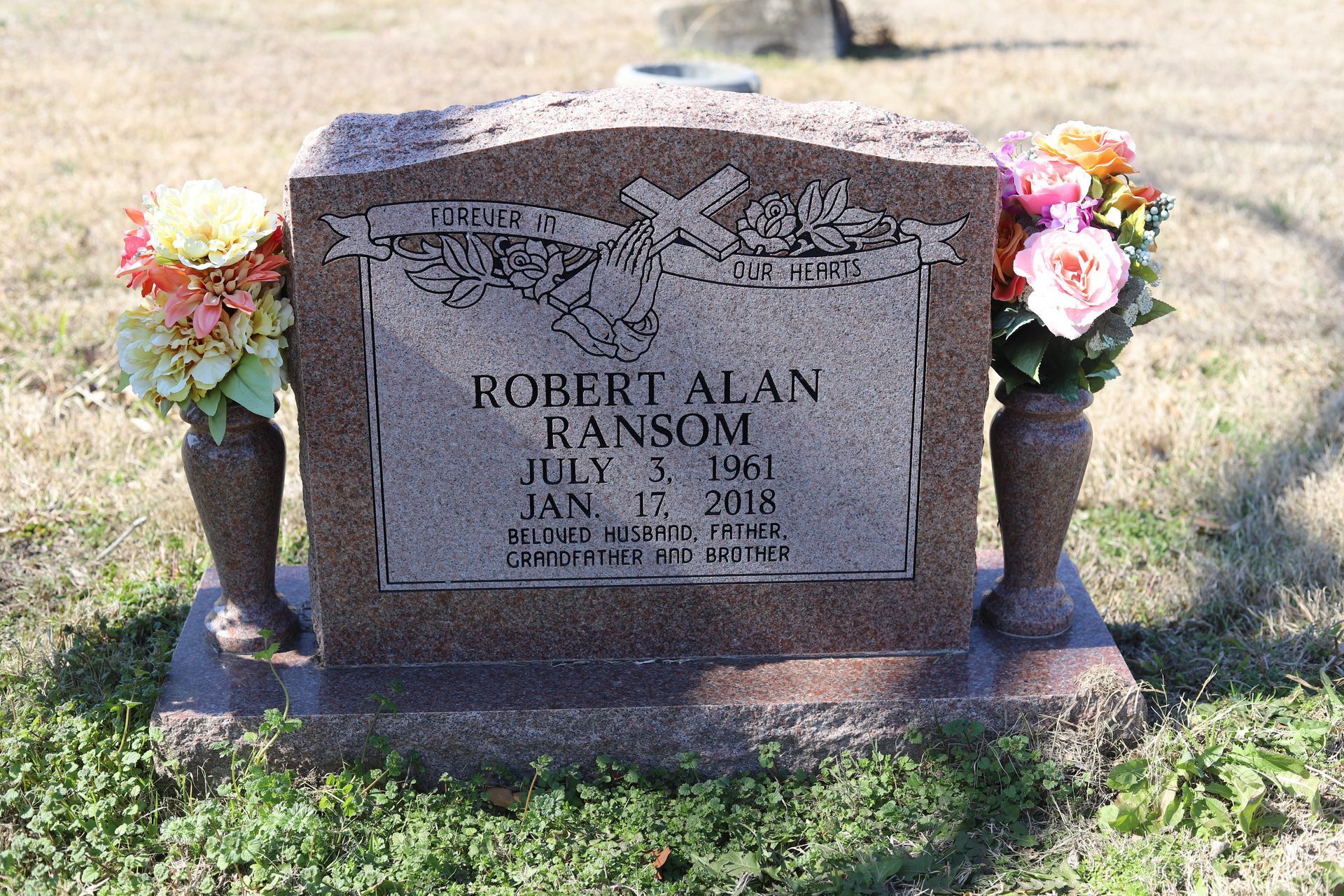 Headstone of Robert Alan Ransom with flowers on either side.