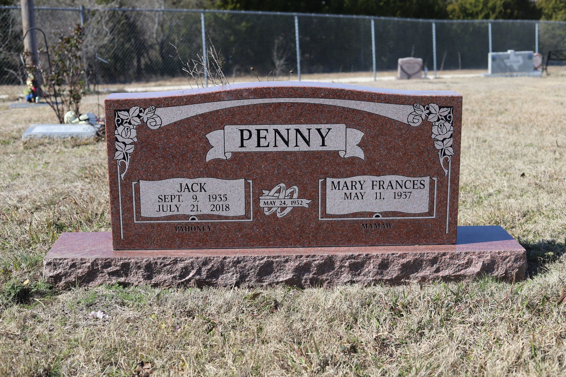 Red granite headstone in a cemetery; reads